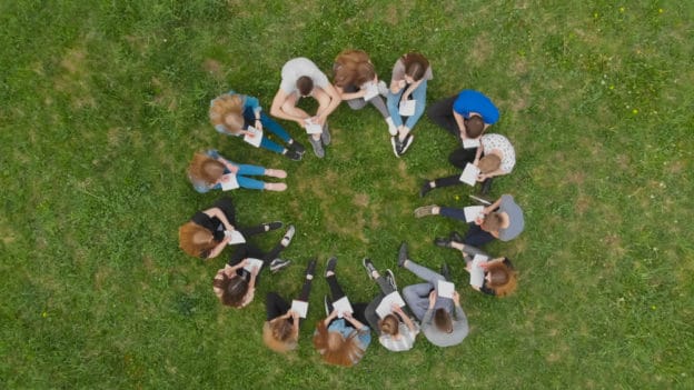 Aerial view of diverse group sitting in circle, discussing Anxiety Across Cultures.