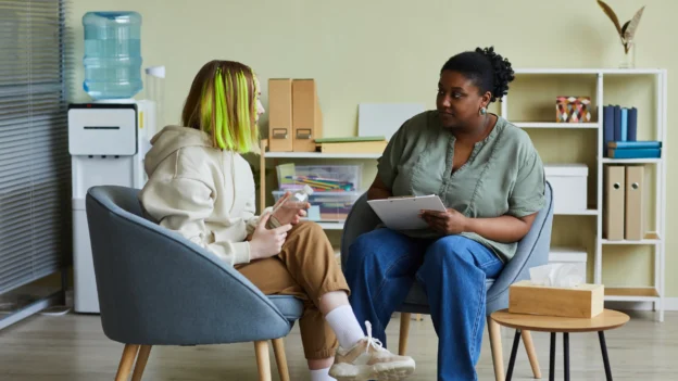 Two women in chairs having a conversation during depression therapy session.