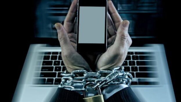 Image of a person in a suit with chains on their wrists, holding a cell phone, depicting internet addiction.