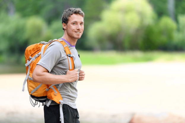 A man with a backpack standing near a river, seeking Depression Treatment with Insurance.